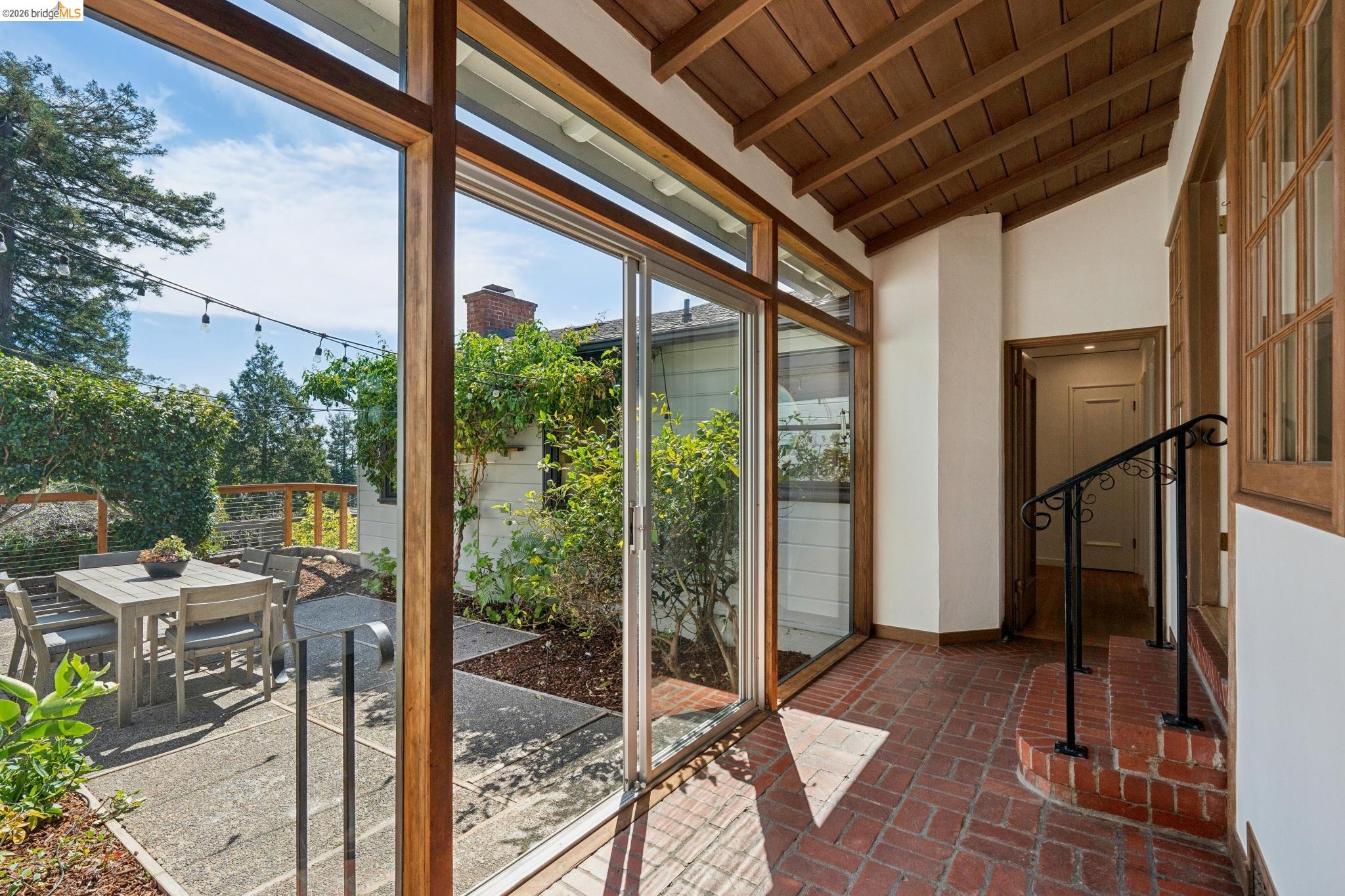 38 Highgate Road Kensington, CA 94707 - Photo 8 of 78 Expansive glass doors and windows, brick flooring, exposed beam ceiling, wrought iron railing, and a private outdoor patio