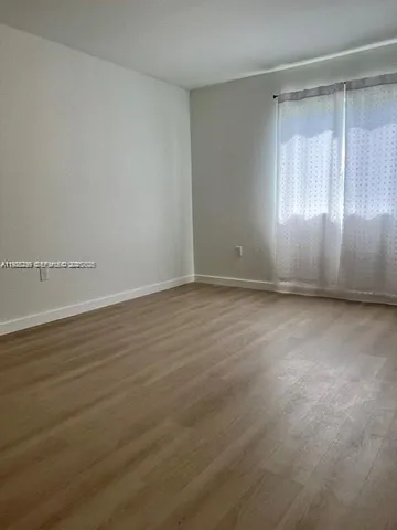 an empty room with wooden floor and windows in it