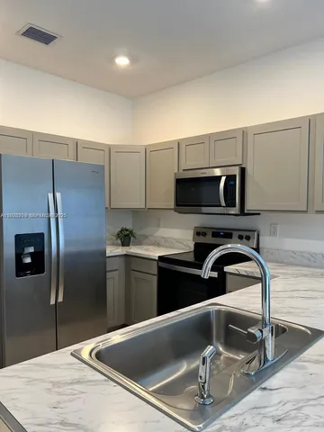 a kitchen with stainless steel appliances granite countertop a sink and a refrigerator