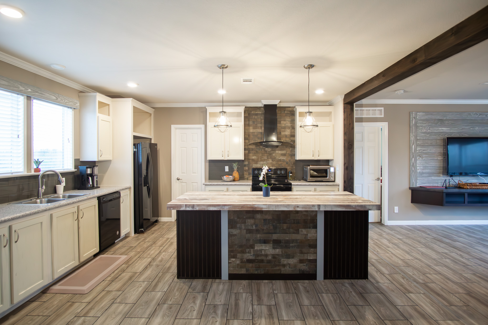 Kitchen featuring crown molding, decorative light fixtures, black appliances, a center island, and wood tiled floors