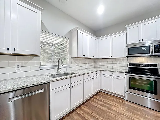 a bathroom with a granite countertop sink a toilet and a large mirror
