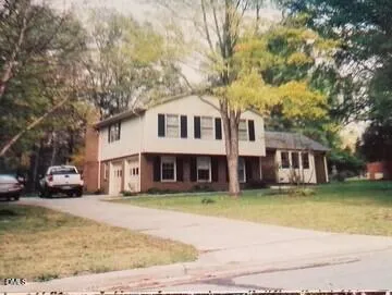 a front view of a house with a garden and trees
