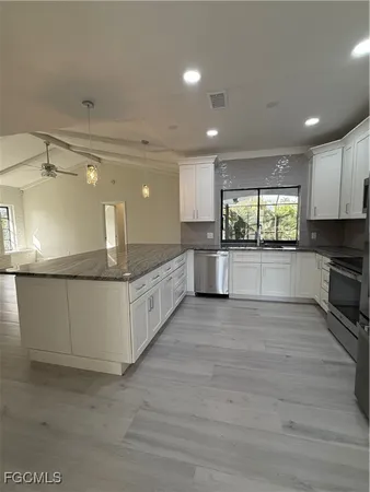 a large kitchen with kitchen island a sink stainless steel appliances and cabinets