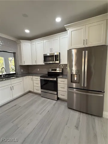 a kitchen with cabinets stainless steel appliances and a window