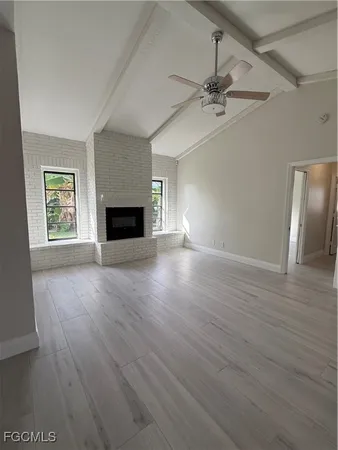 an empty room with windows fireplace and wooden floor