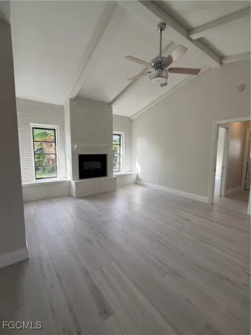 an empty room with windows fireplace and wooden floor