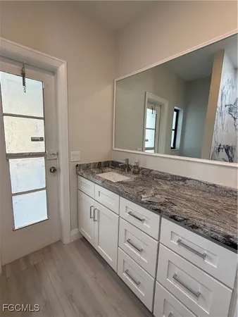 a bathroom with a granite countertop sink and a mirror