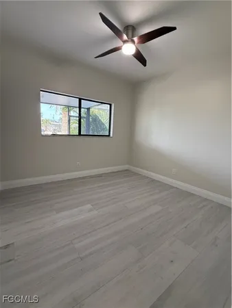 an empty room with wooden floor ceiling fan and windows