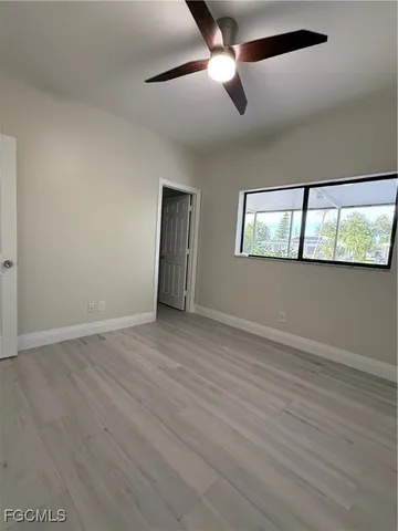 an empty room with wooden floor fan and windows