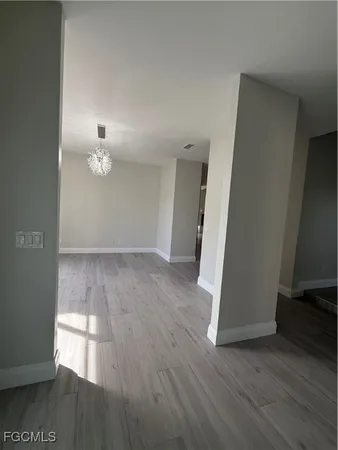 an empty room with wooden floor table and chairs