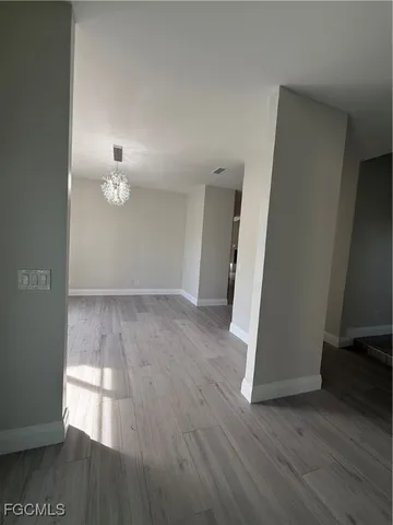 an empty room with wooden floor table and chairs