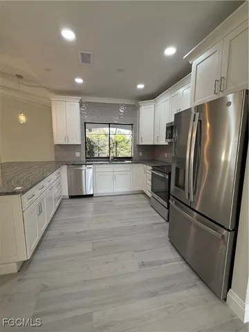 a kitchen with granite countertop a refrigerator and a sink