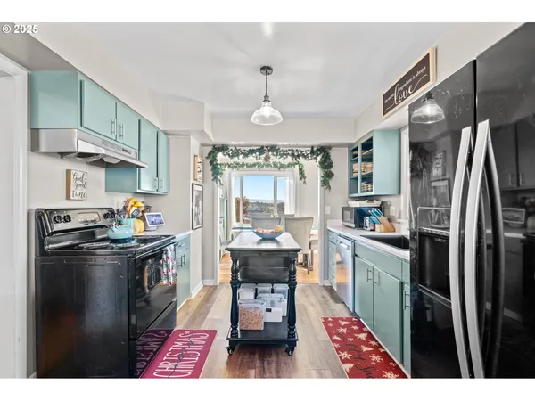 a kitchen with stainless steel appliances a dining table chairs stove refrigerator and cabinets