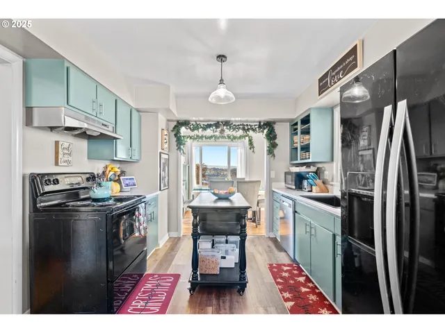 a kitchen with stainless steel appliances a dining table chairs stove refrigerator and cabinets