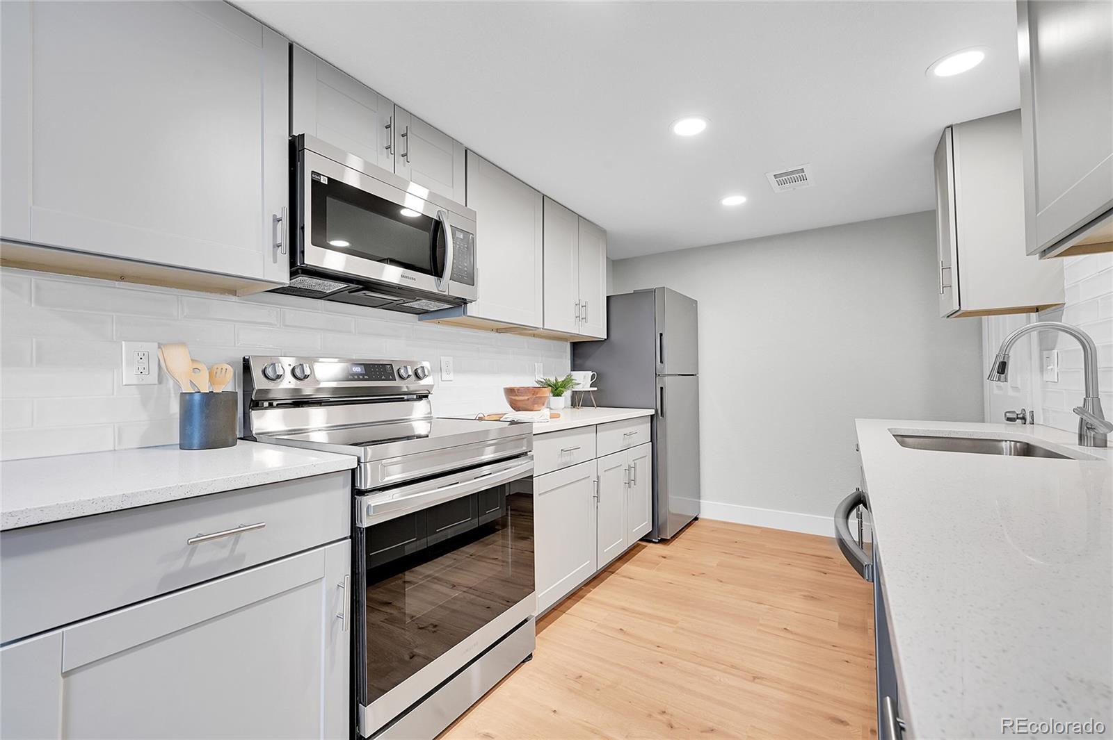 1344 Sable Boulevard Aurora, CO 80011 - Photo 12 of 31 a kitchen with stainless steel appliances granite countertop a sink and a stove top oven with white cabinets