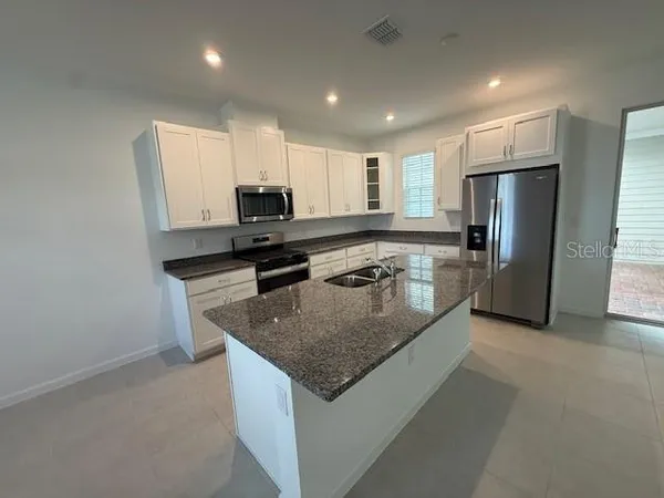 a kitchen with stainless steel appliances granite countertop a sink refrigerator and microwave