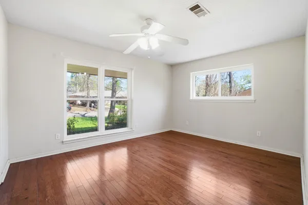 a view of an empty room with wooden floor and a window