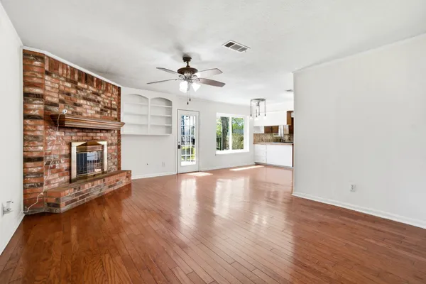 an empty room with wooden floor a fireplace and a window