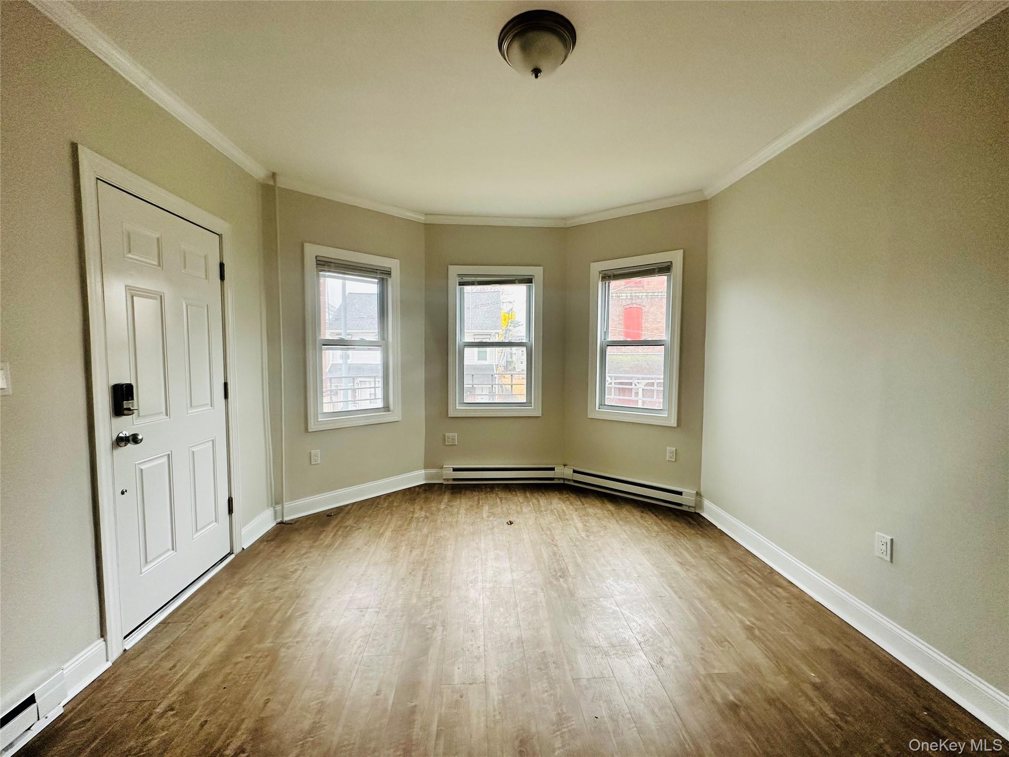 151 Cannon Street, Unit 3 Poughkeepsie, NY 12601 - Photo 2 of 12 Unfurnished room with ornamental molding, wood-type flooring, and a baseboard heating unit