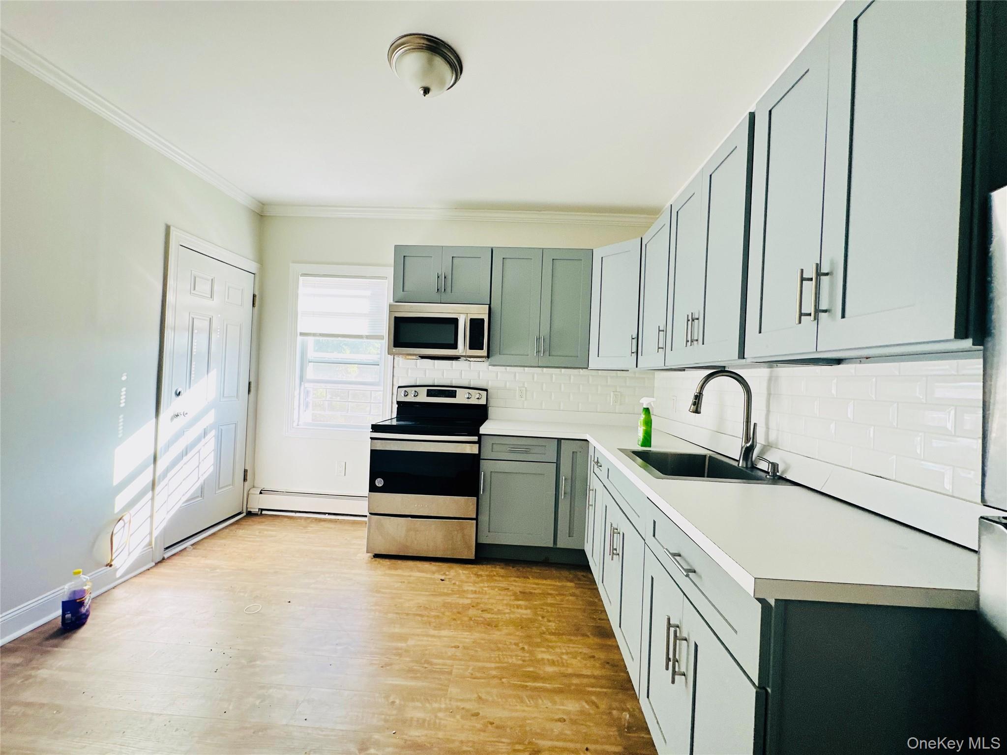 151 Cannon Street, Unit 3 Poughkeepsie, NY 12601 - Photo 4 of 12 Kitchen featuring sink, light hardwood / wood-style flooring, ornamental molding, a baseboard radiator, and stainless steel appliances