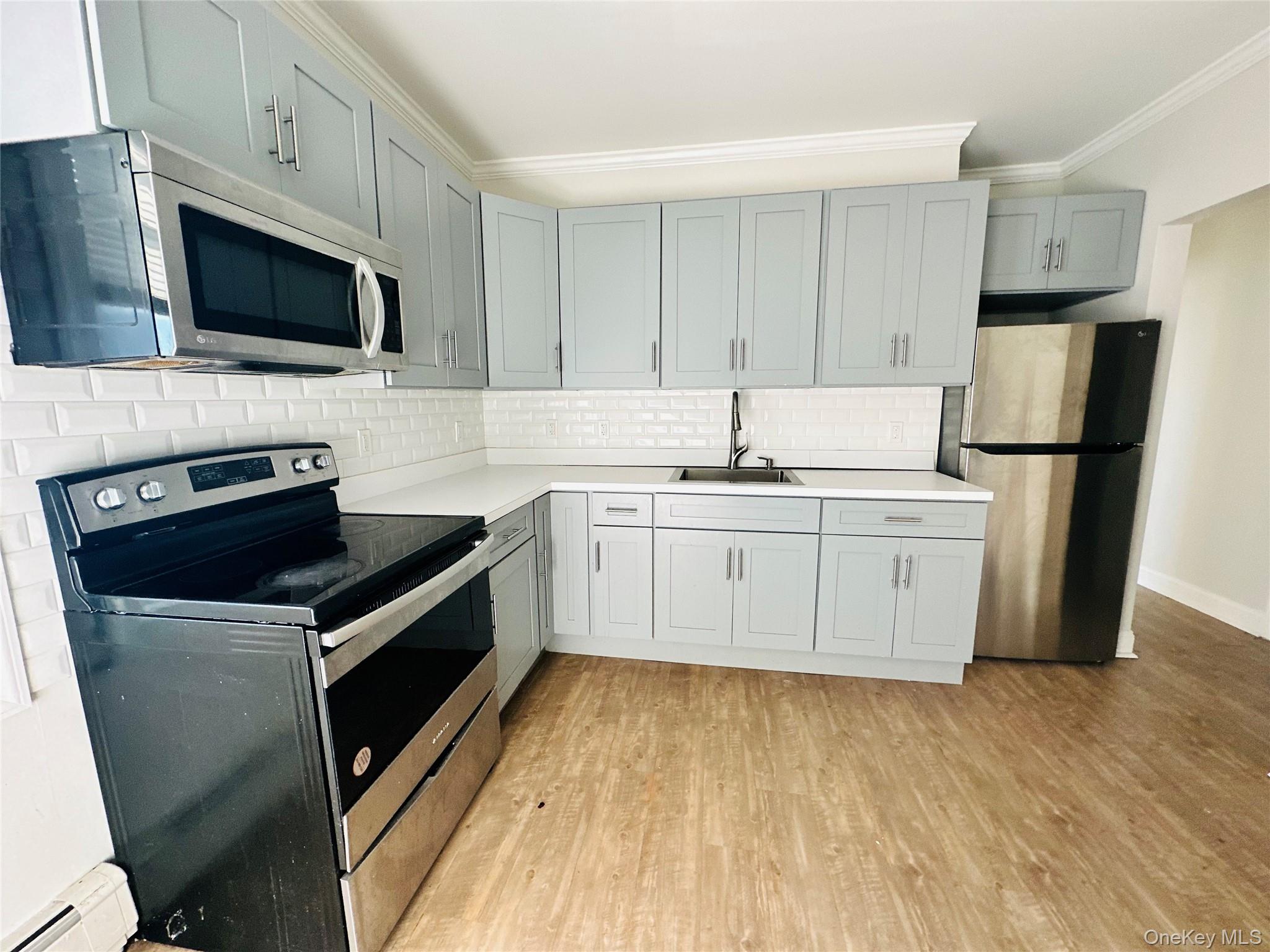 151 Cannon Street, Unit 3 Poughkeepsie, NY 12601 - Photo 5 of 12 Kitchen featuring decorative backsplash, appliances with stainless steel finishes, ornamental molding, sink, and light hardwood / wood-style flooring
