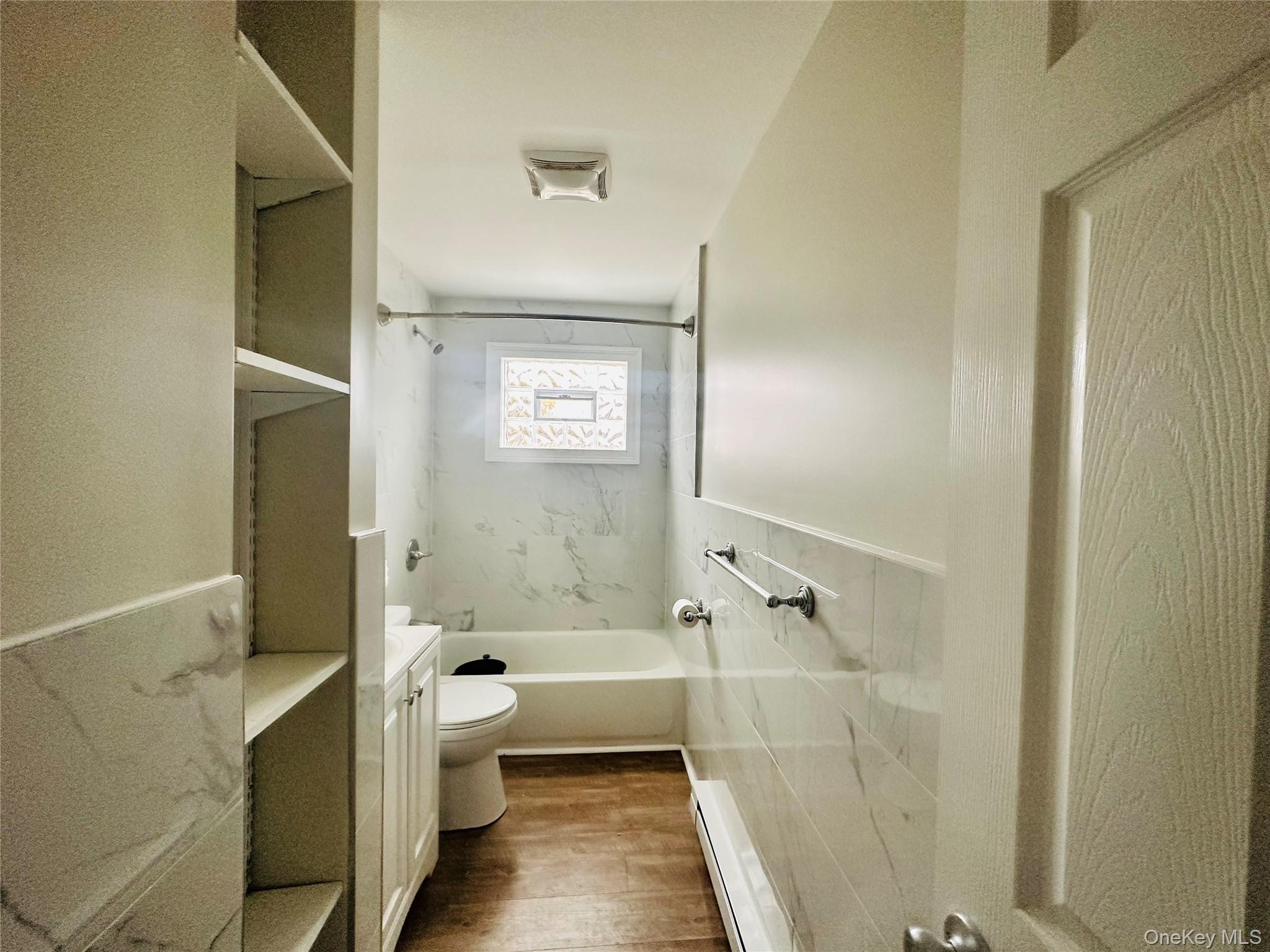 151 Cannon Street, Unit 3 Poughkeepsie, NY 12601 - Photo 9 of 12 Full bathroom with vanity, tiled shower / bath combo, a baseboard radiator, hardwood / wood-style floors, and toilet