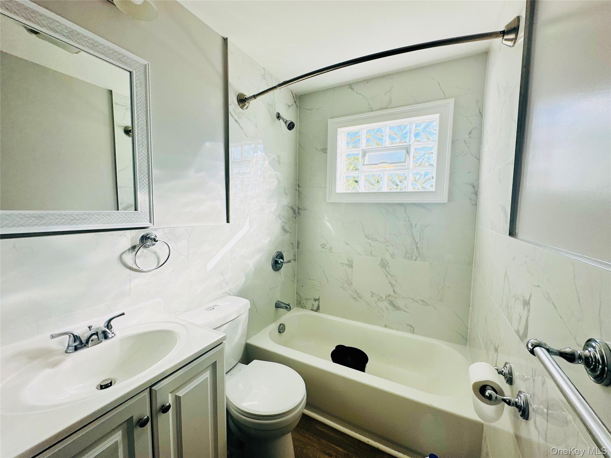 151 Cannon Street, Unit 3 Poughkeepsie, NY 12601 - Photo 10 of 12 Full bathroom featuring tiled shower / bath combo, hardwood / wood-style floors, toilet, vanity, and tile walls