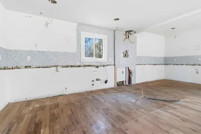 a view of empty room with wooden floor and window