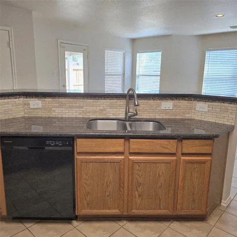 a kitchen with granite countertop cabinets sink and window