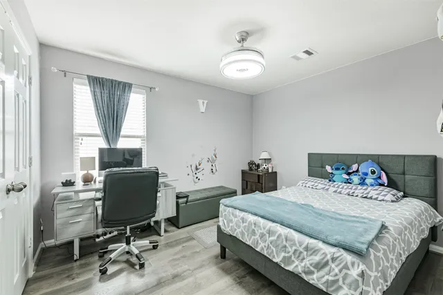 a bedroom with a bed a desk and chair with window