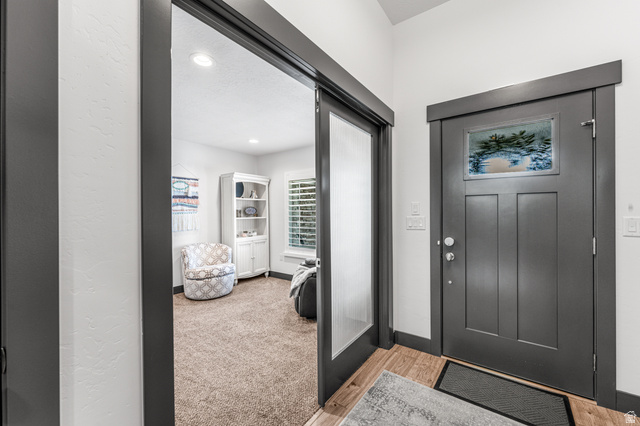 313 Old Maple Road South Weber, UT 84405 - Photo 4 of 35 Entryway featuring a dark gray paneled door with decorative glass inlay, wood-finish flooring, and a pocket door with frosted glass paneling