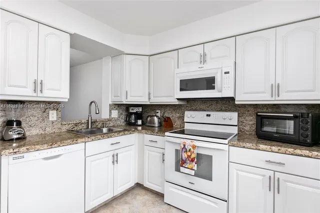 a kitchen with granite countertop white cabinets and white appliances
