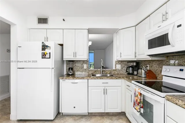 a kitchen with stainless steel appliances granite countertop white cabinets and a refrigerator