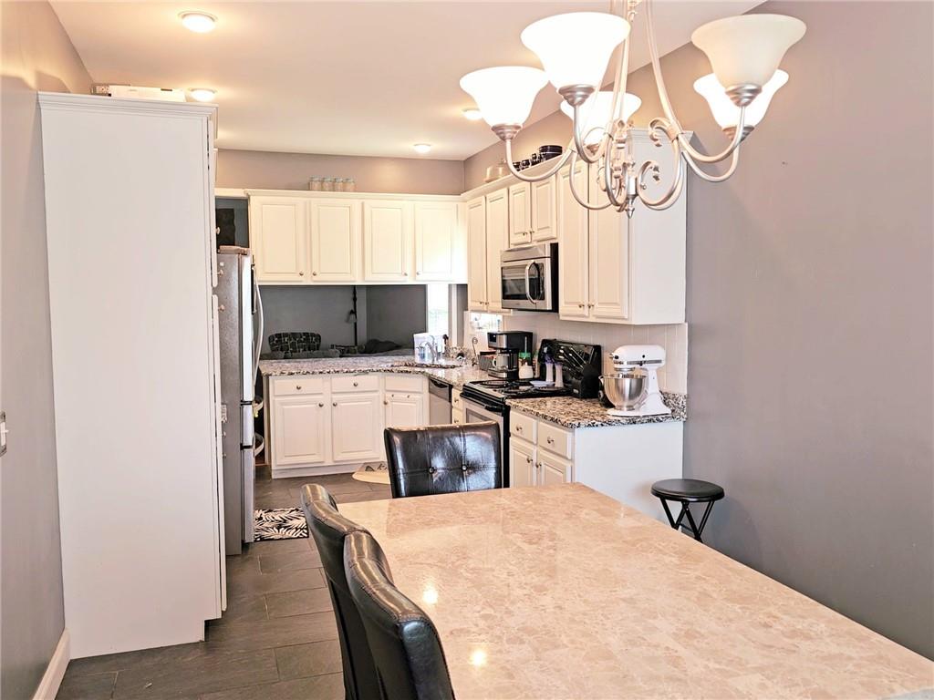 147 Crest Winds Drive Clarkesville, GA 30523 - Photo 8 of 17 a kitchen with a refrigerator a stove top oven a sink a dining table and chairs