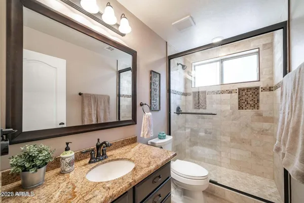 a bathroom with a granite countertop sink toilet a mirror and shower