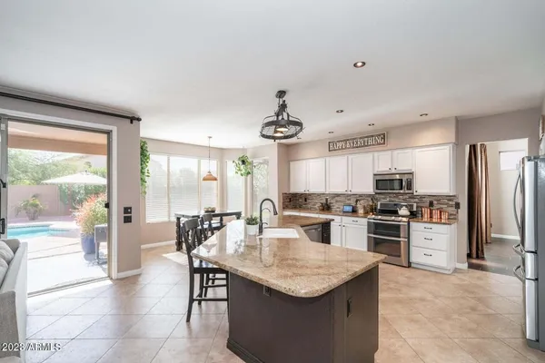 a kitchen with stainless steel appliances granite countertop a table chairs and a refrigerator