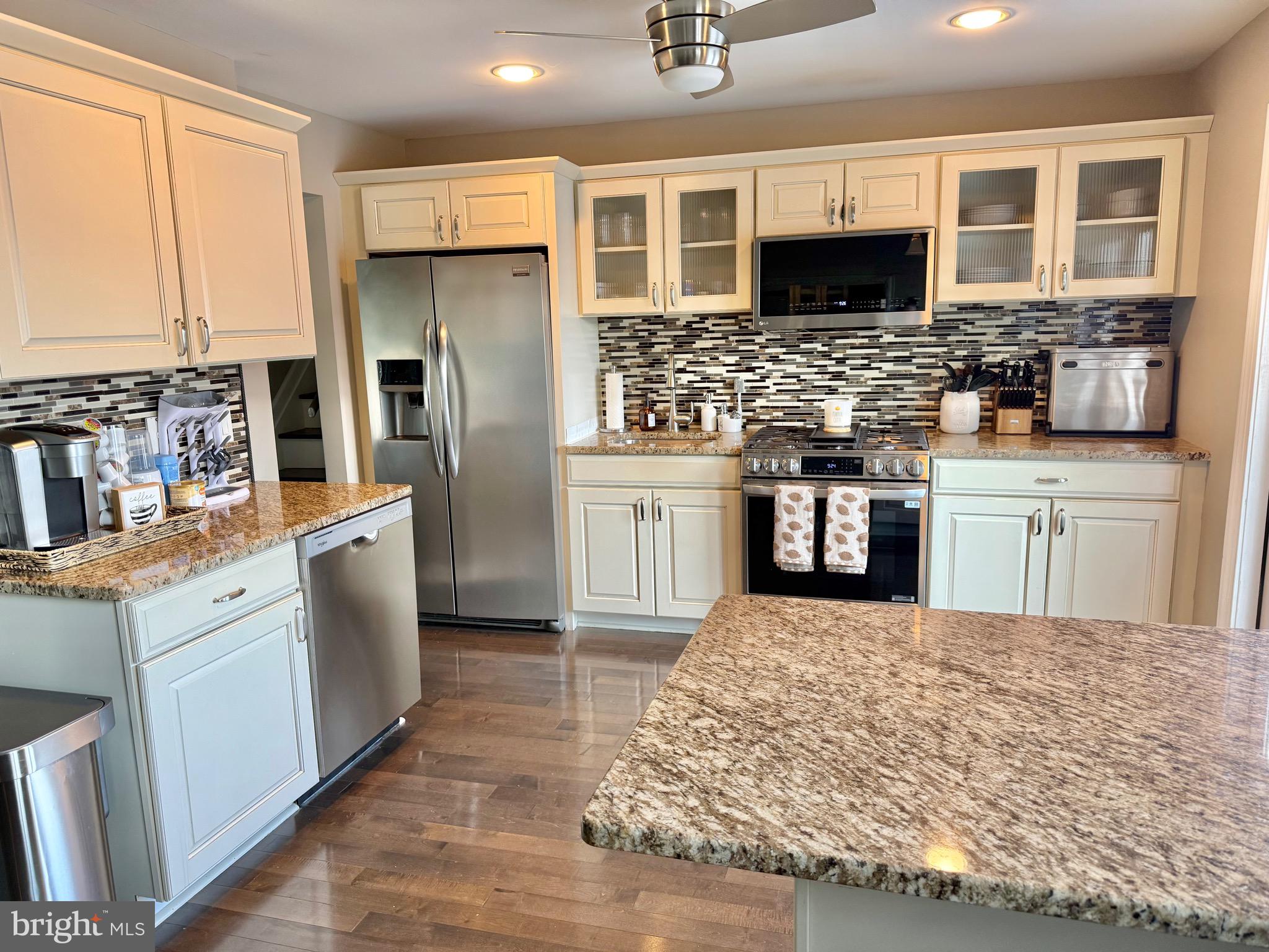 30 Rock Royal Road Hamilton, NJ 08620 - Photo 32 of 54 a kitchen with stainless steel appliances kitchen island granite countertop a stove top oven a sink a refrigerator white cabinets and wooden floor