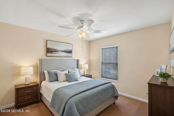 a bedroom with a bed and a lamp on the dresser