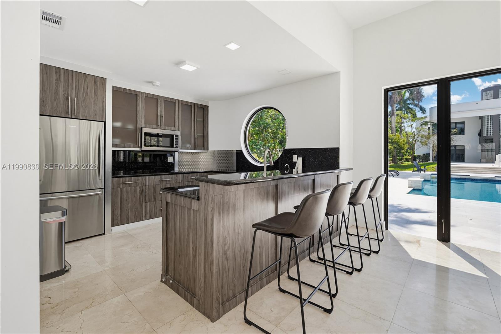 14401 Southwest 63rd Street Southwest Ranches, FL 33330 - Photo 68 of 81 a kitchen with stainless steel appliances granite countertop a stove a refrigerator a microwave a dining table and chairs