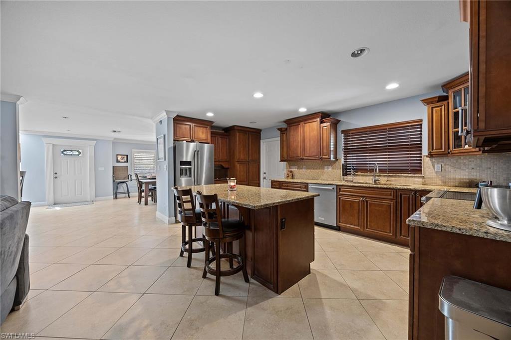 6574 Trail Boulevard Naples, FL 34108 - Photo 16 of 40 a kitchen with stainless steel appliances granite countertop a sink dishwasher stove top oven and cabinets