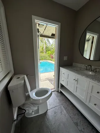 a bathroom with a granite countertop toilet a sink and a mirror