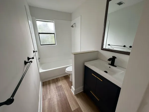 a bathroom with a bathtub sink vanity granite and a toilet