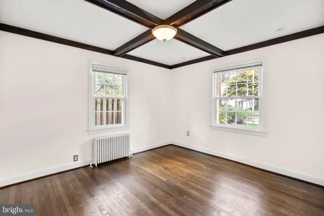 an empty room with wooden floor chandelier fan and windows