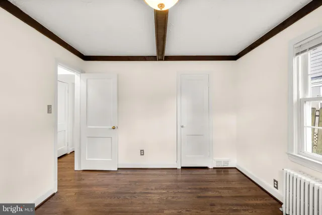 a view of an empty room with window and wooden floor