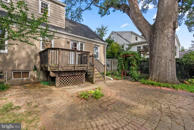 a view of a brick house with a small yard and large tree