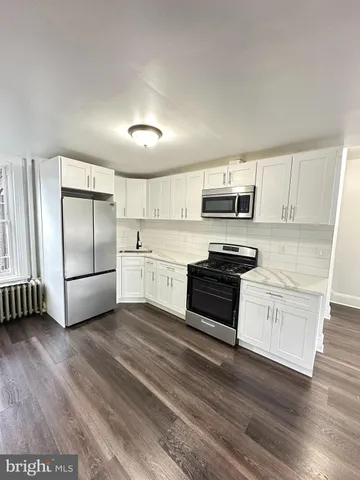 a kitchen with granite countertop a refrigerator and a stove top oven