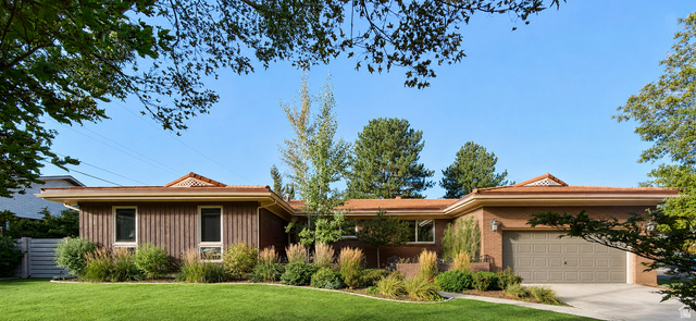Front exterior with a brick and vertical wood siding facade, a two-car garage, and a lush lawn