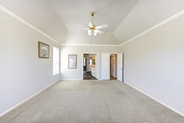 a view of an empty room with chandelier fan
