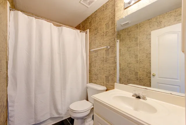 an empty room with chandelier fan and windows