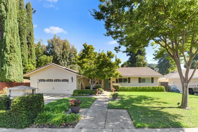 a view of house with garden and tall trees